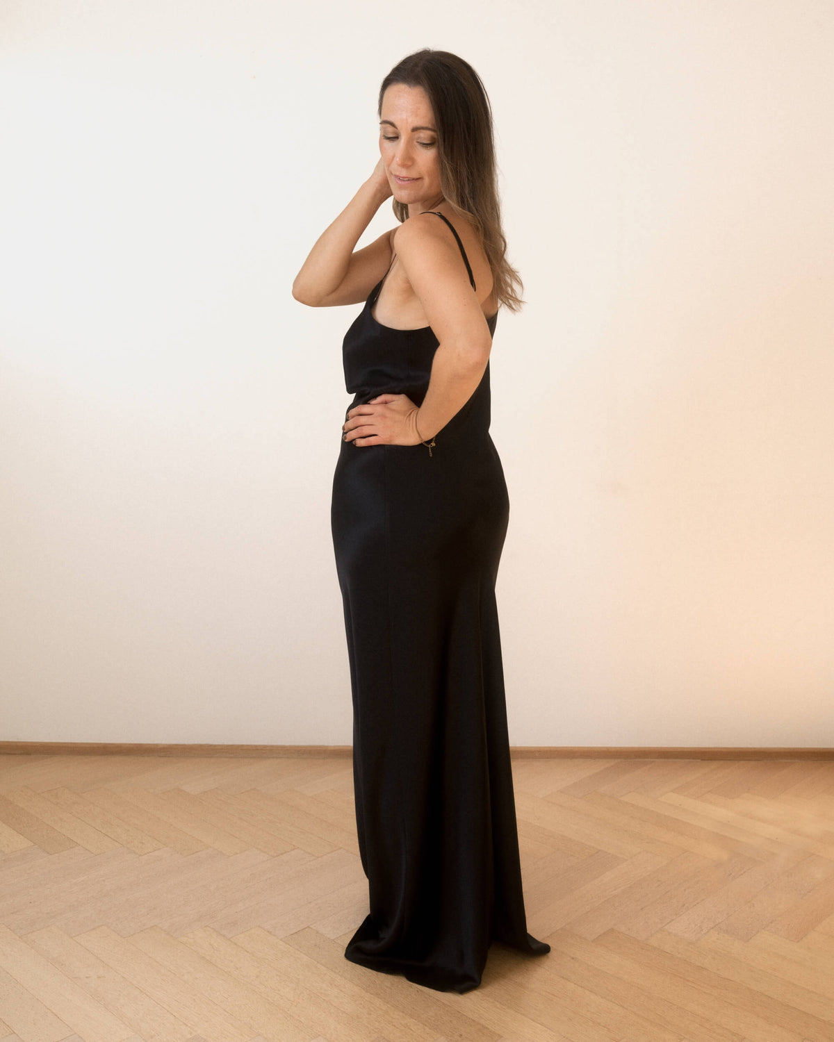 Leonora gulvlang silkenatkjole i sort med smalle stropper, vist fra siden på model
